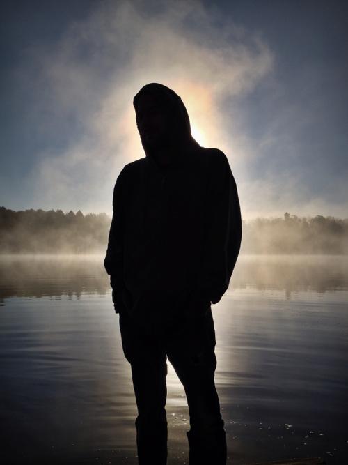 Silhouette of person in front of a misty lake