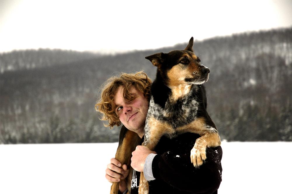 Man standing on frozen lake with dog on his shoulders