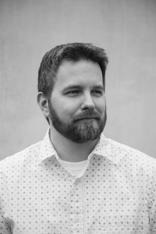 Black and white portrait of man with beard in patterned button down shirt