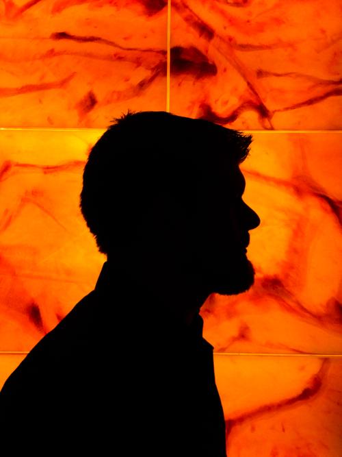 Silhouette of a man with beard against an orange backlight stone wall