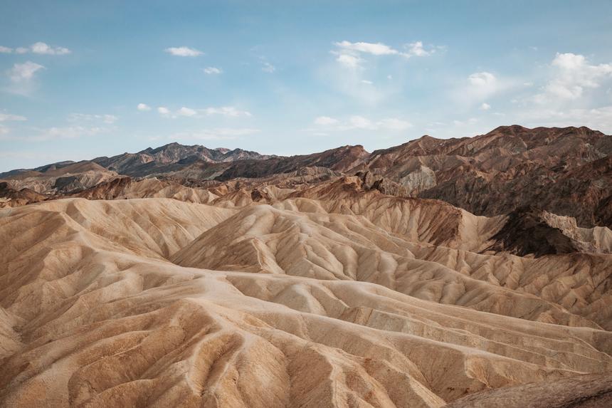 Multicolored sand and rock formations against a blue sky.