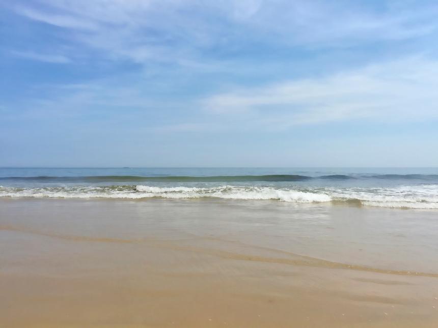 A sandy shore with gently breaking waves.