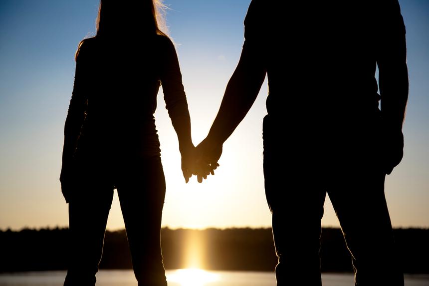 A backlit couple holding hands